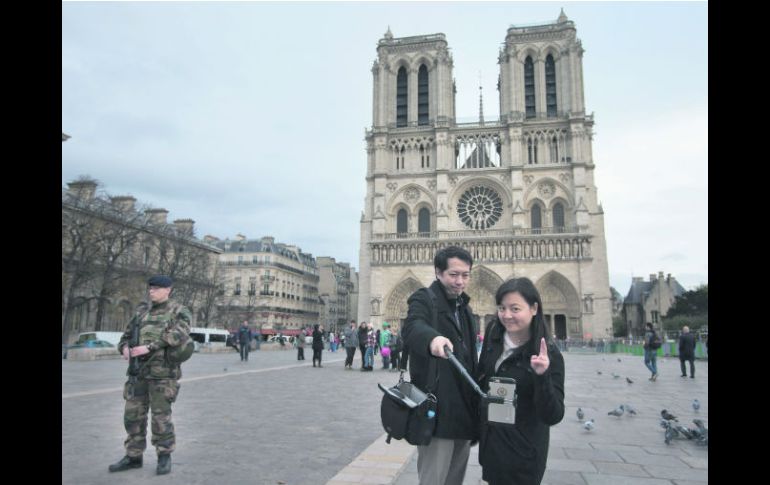 Dos turistas se toman una fotografía en la catedral de Notre Dame, mientras un soldado francés vigila la zona. AP /