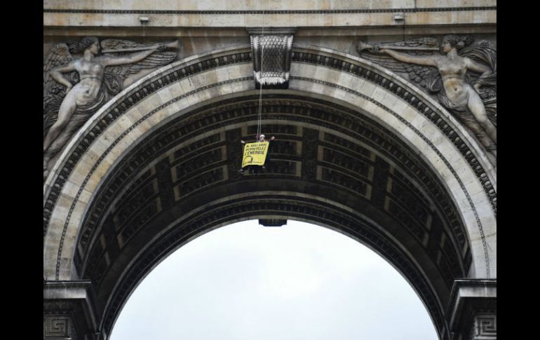 Un ecologista se colgó a 30 metros de altura con banderas amarillas donde se leía: ''Hollande, renueve la energía''. AFP / M. Bureau