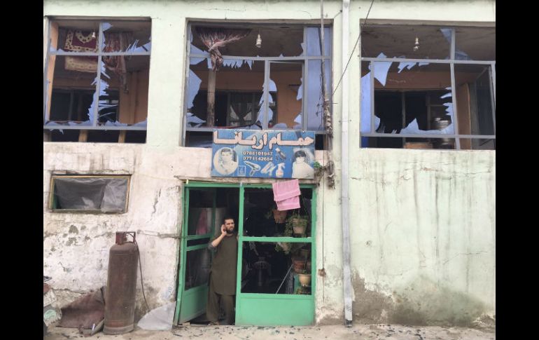 Un hombre habla por teléfono desde la entrada de su tienda, dañada por la explosión. EFE / J. Jalali