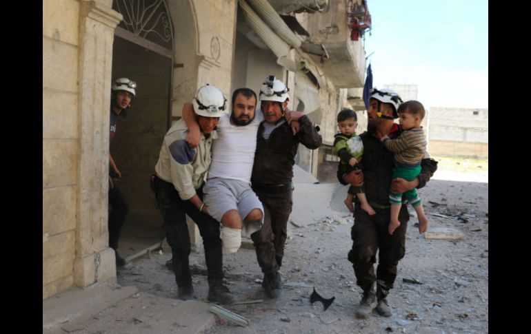 Voluntarios evacuan a un hombre lisiado y a varios niños de un edificio dañado por los recientes bombardeos. AFP / A. Alhalbi