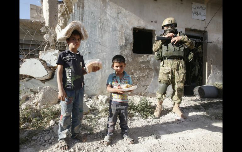 Niños sirios posan con alimentos y ayuda humanitaria entregada por soldados rusos. EFE / S. Chirikov
