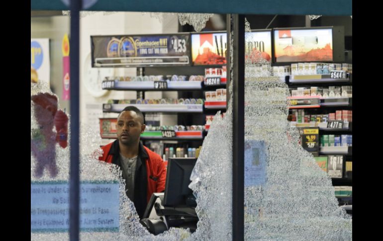 El trabajador de una tienda de autoservicio observa los daños ocasionados por el tiroteo. AP / L. Otero