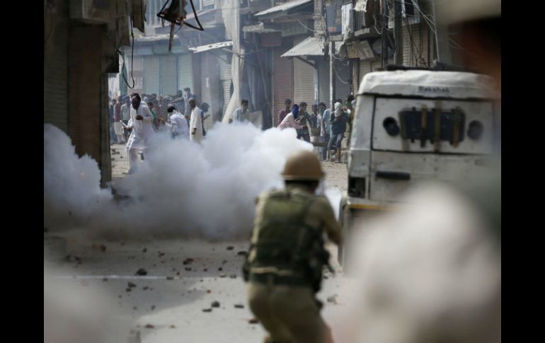 Varios jóvenes se protegen contra el gas lacrimógeno lanzado por la policía india durante unas revueltas en Srinagar. EFE / F. Khan