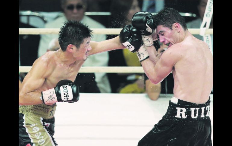 Hozumi Hasegawa golpea con la izquierda a Hugo 'Cuatito' Ruiz (derecha) durante la pelea por el título del CMB peso supergallo. AFP /