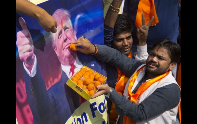 Un miembro de Hindu Sena 'alimenta' un retrato de Trump con dulces. AP / M. Swarup
