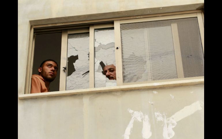 Dos habitantes vislumbran los daños en su vivienda tras el tiroteo. EFE / A. Badarneh
