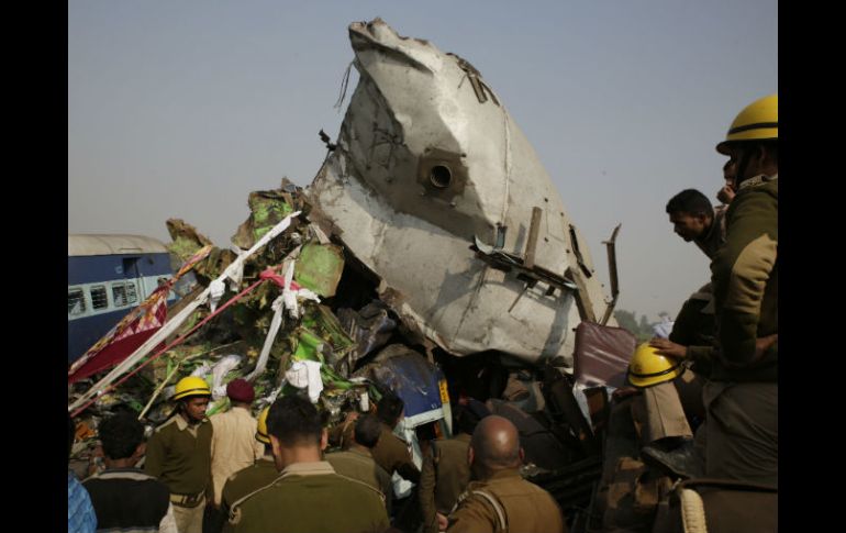 Bomberos intentan mover uno de los vagones despedazados ante la mirada de decenas de curiosos. AP / R. Kumar