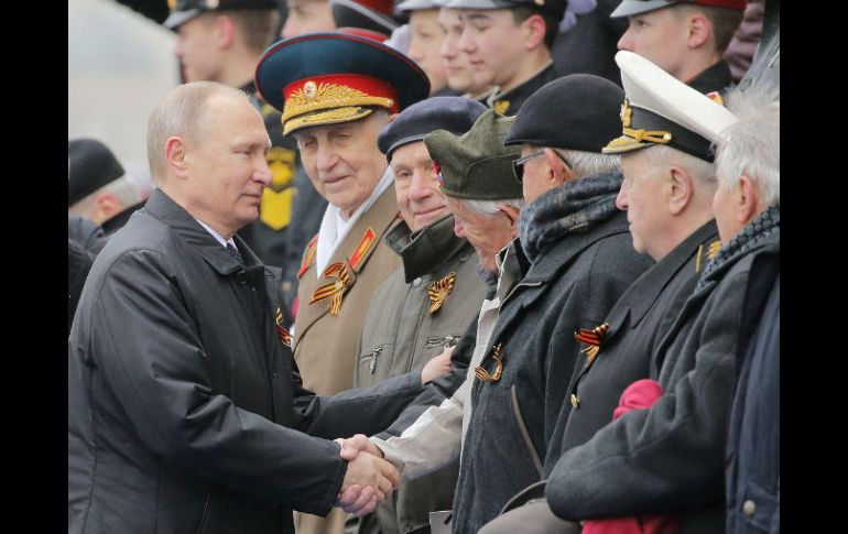 Vladímir Putin (i), estrecha la mano a varios veteranos de la II Guerra Mundial durante el desfile militar por el Día de la Victoria. EFE / Y. Kochetkov