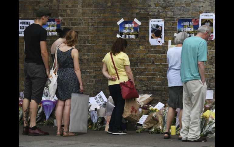 Varias personas observan los mensajes de apoyo, flores y velas dejadas en el lugar del ataque en Finsbury Park. EFE / A. Rain