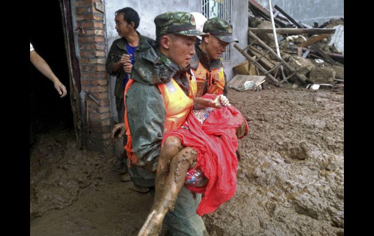 Rescatistas llevan a una persona que lograron sacar de entre toneladas de lodo y tierra, a causa de las lluvias. EFE /  S. Mingshi