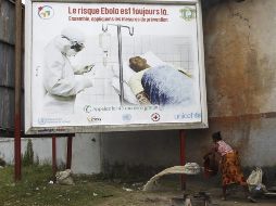 Una mujer desocupa un balde con agua debajo de una valla de advertencia sobre la presencia del virus del ébola, el 25 de agosto de 2014. EFE/ARCHIVO