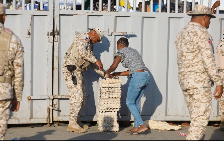 Un soldado ayuda a una mujer mientras cruza la frontera entre Quanamienthe en Haití y Dajabón en República Dominicana para trabajar en el mercado binacional. AFP